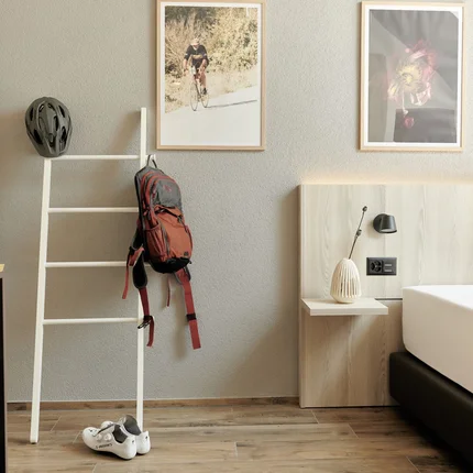 Hotelzimmer mit Fahrradzubehör neben einem Bett und dekorativen Bildern