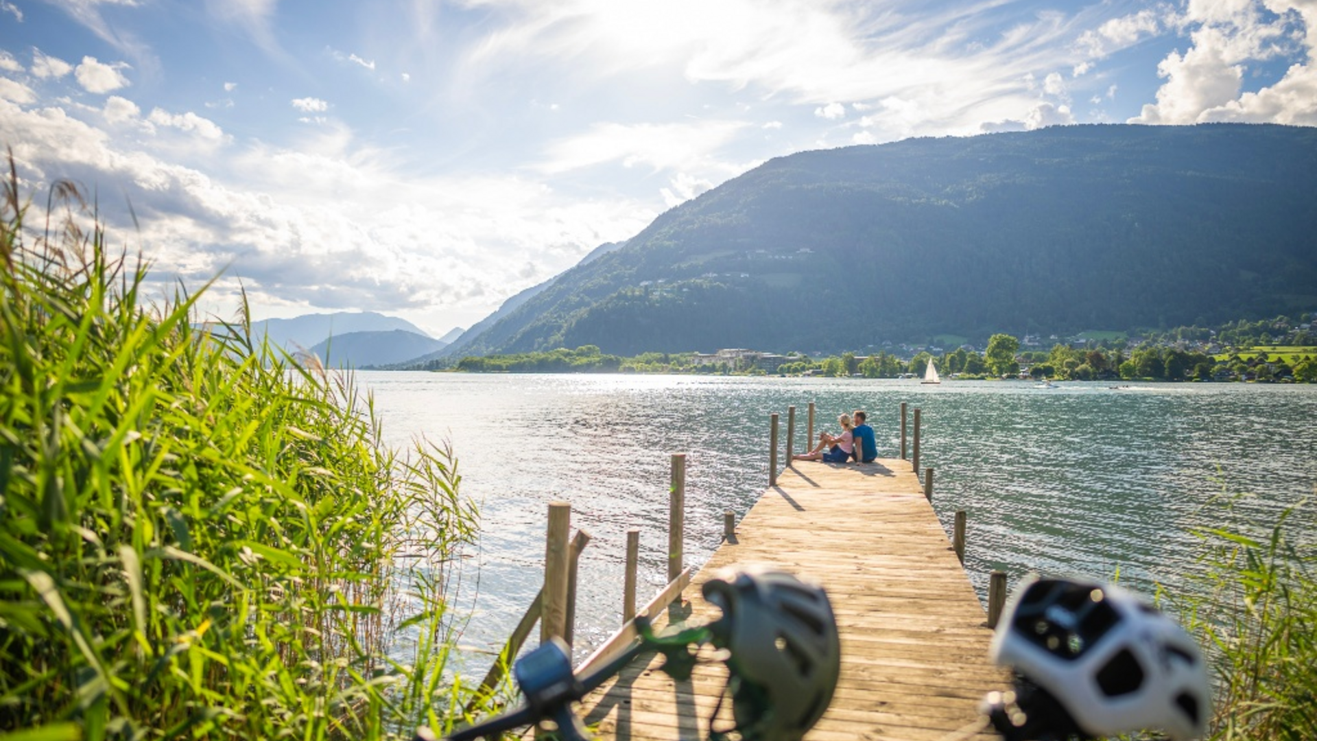 Couple sitting on a pier by a lake with mountains in the background