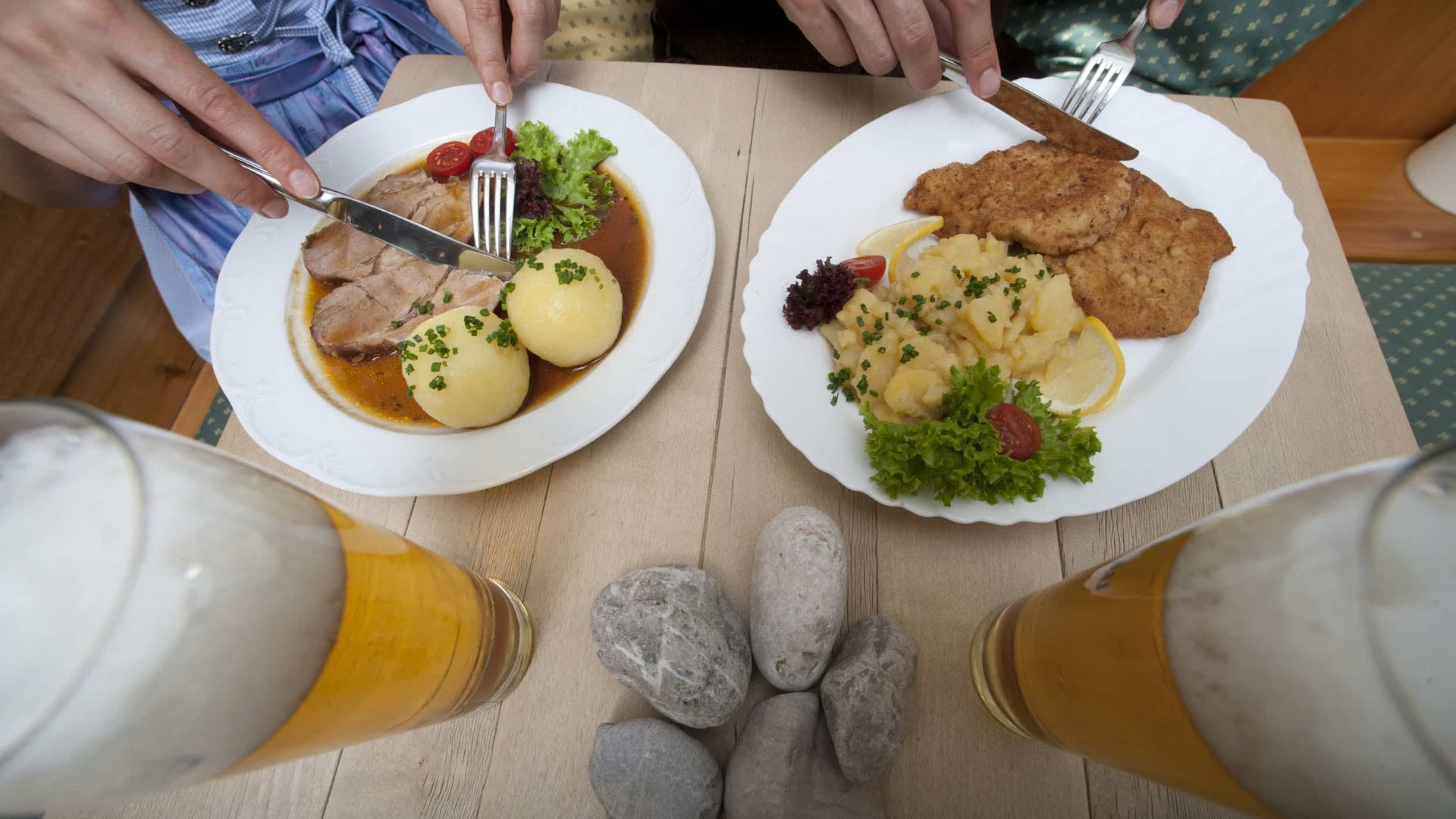 People eating traditional German meals with beer on a wooden table