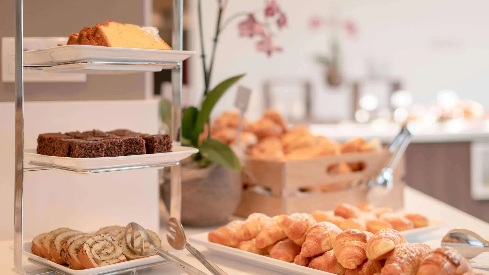 Tablett mit verschiedenen Gebäckstücken und Croissants auf weißem Tisch