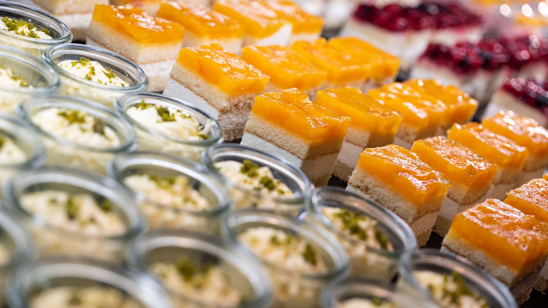 Close-up of layered desserts and small cakes arranged in rows