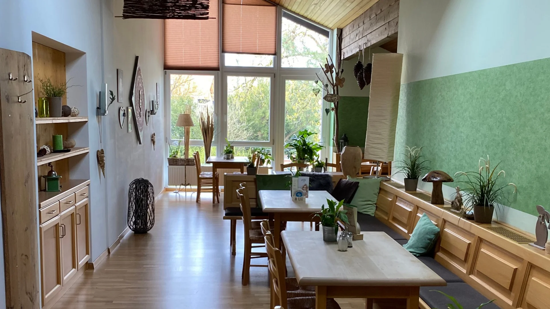 Gemütliches Esszimmer mit Holzmöbeln und Pflanzen neben großen Fenstern