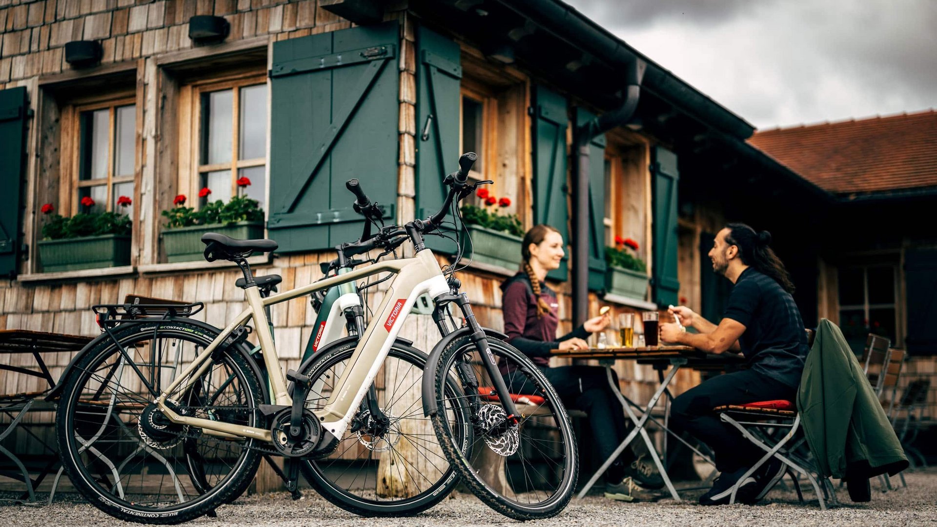 Victoria Two people sitting outdoors at a table near parked e-bikes