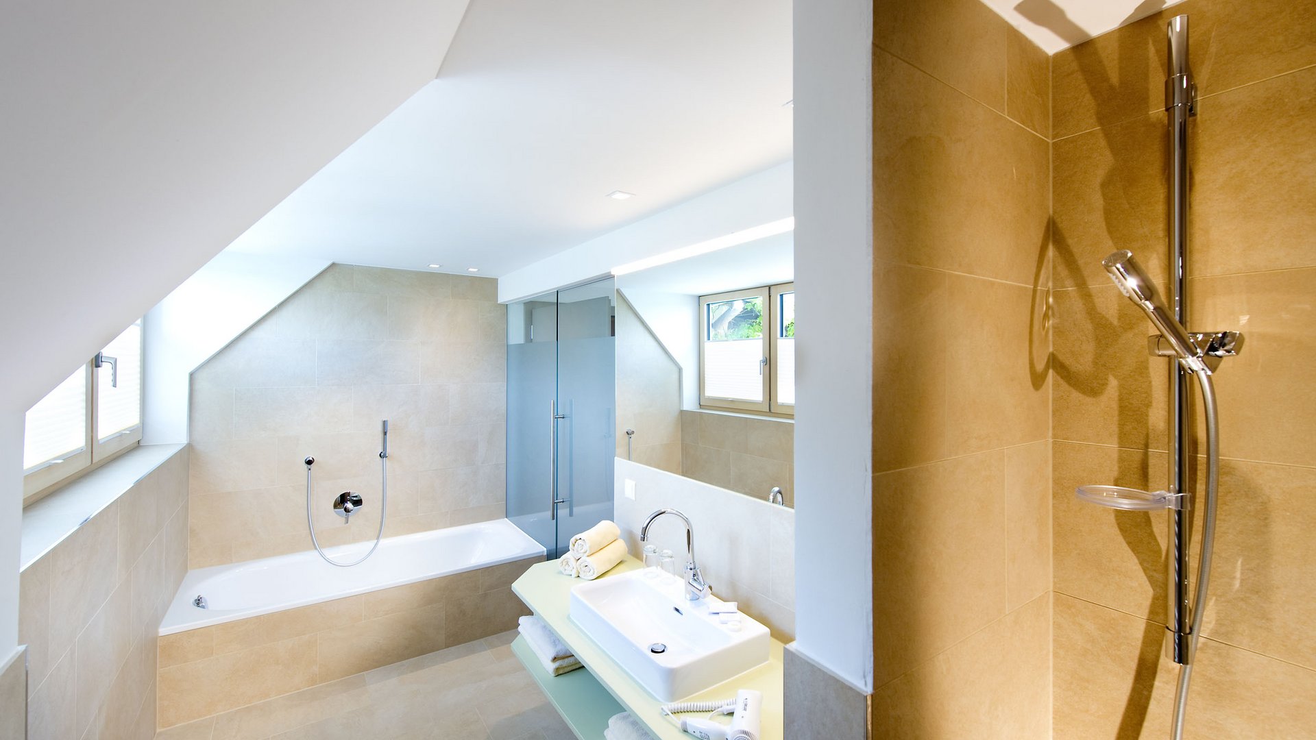 Modern bathroom with bathtub, shower, and sink under slanted ceiling