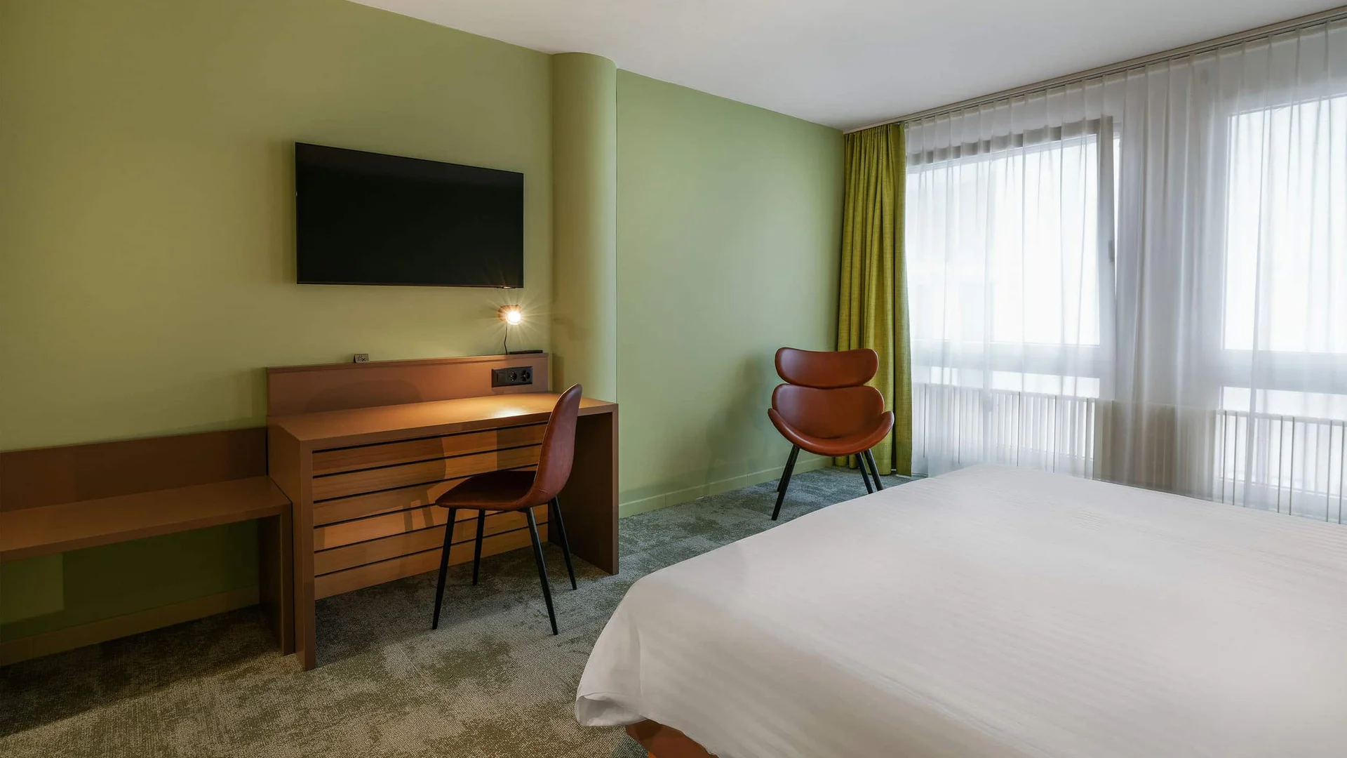 Modern hotelkamer met groene muren en helder wit bed