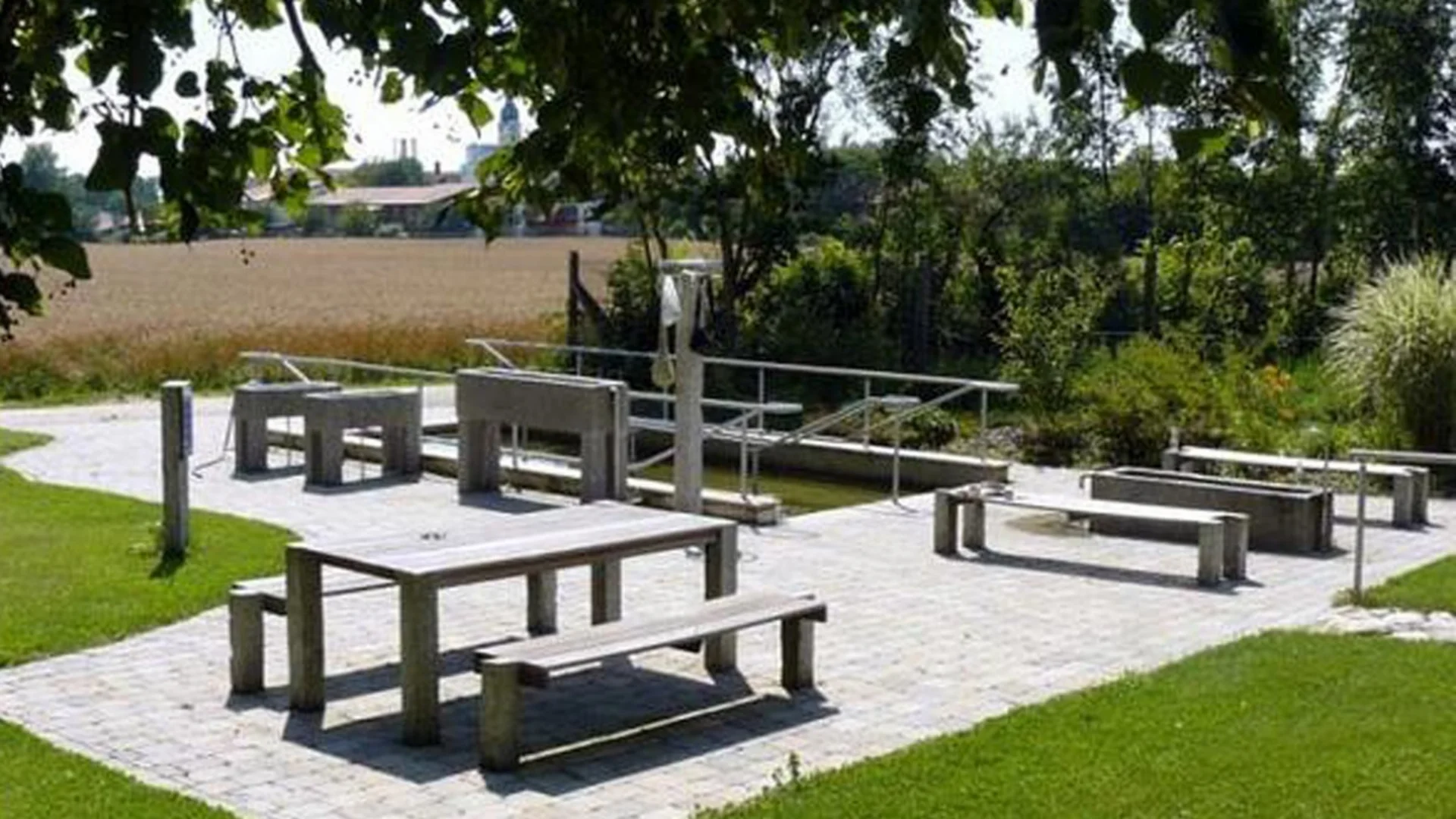 Holzbank und Tisch im Freien mit grünem Gras und Bäumen im Hintergrund