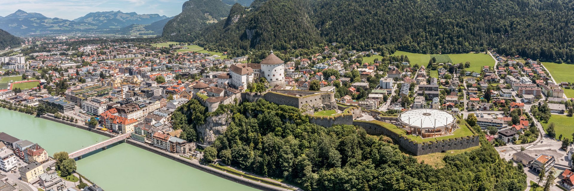 Panoramic view of Kufstein town with fortress and Inn river by forested mountains