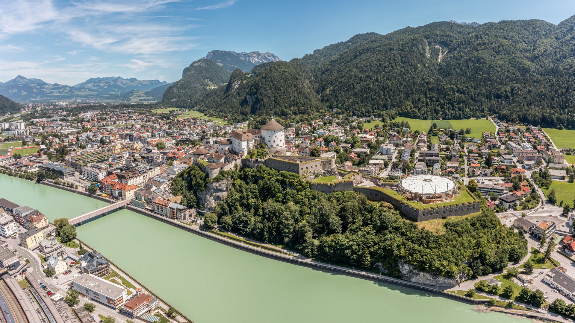 Panoramic view of Kufstein town with fortress and Inn river by forested mountains