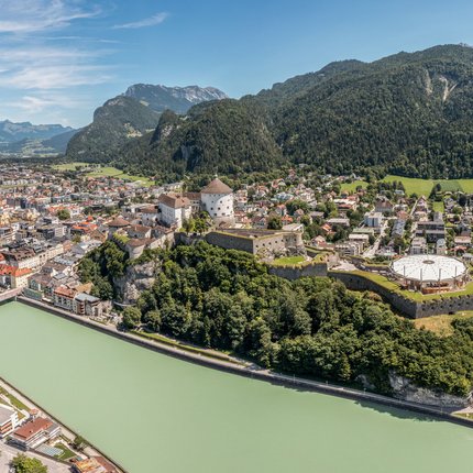Panoramic view of Kufstein town with fortress and Inn river by forested mountains
