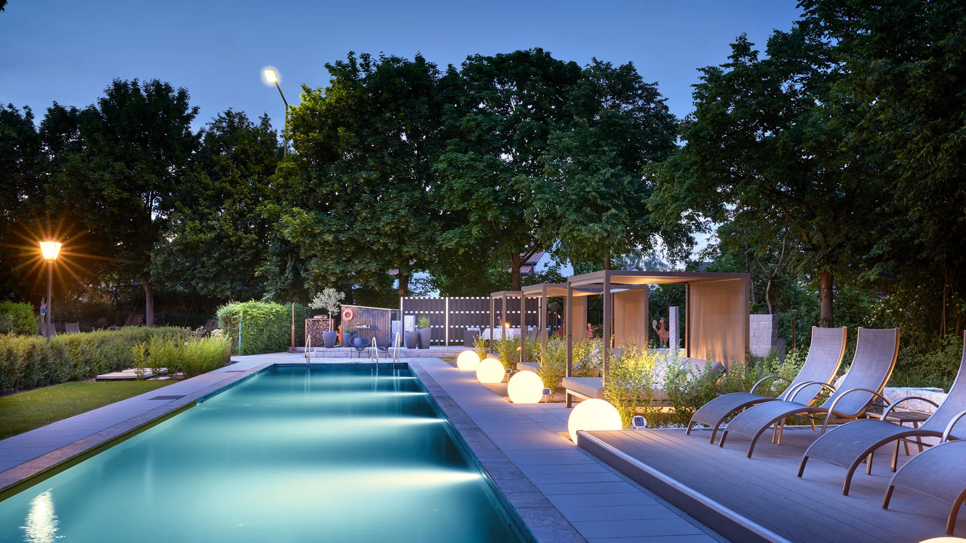 Garden & Spa Hotel das Götzfried **** © Michael Huber Fotographie Verlichte buitenzwembad met ligstoelen en cabana's bij schemering