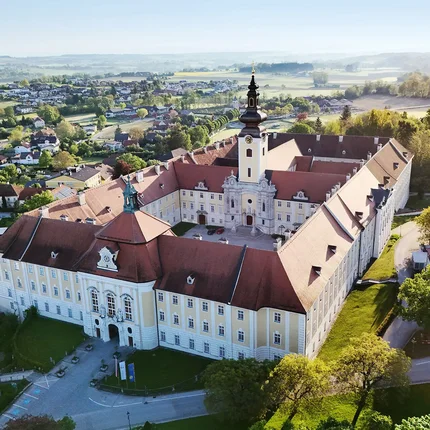 Most-Radroute Luftaufnahme eines historischen Klostergebäudes mit Kirchturm und umliegender Landschaft