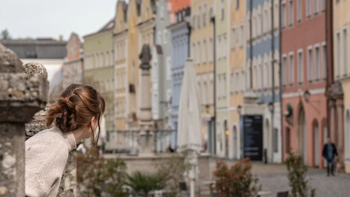 Frau schaut auf eine Straße mit bunten Häusern und Pflastersteinen