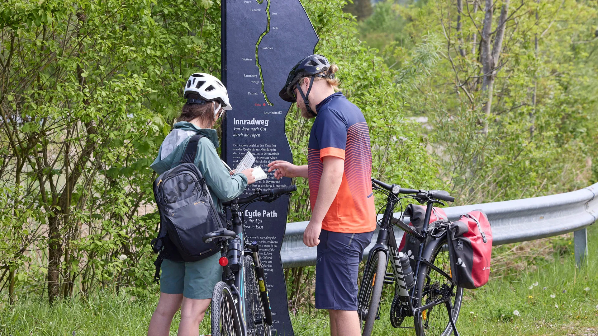 Zwei Radfahrer lesen eine Infotafel am Innradweg in Tirol