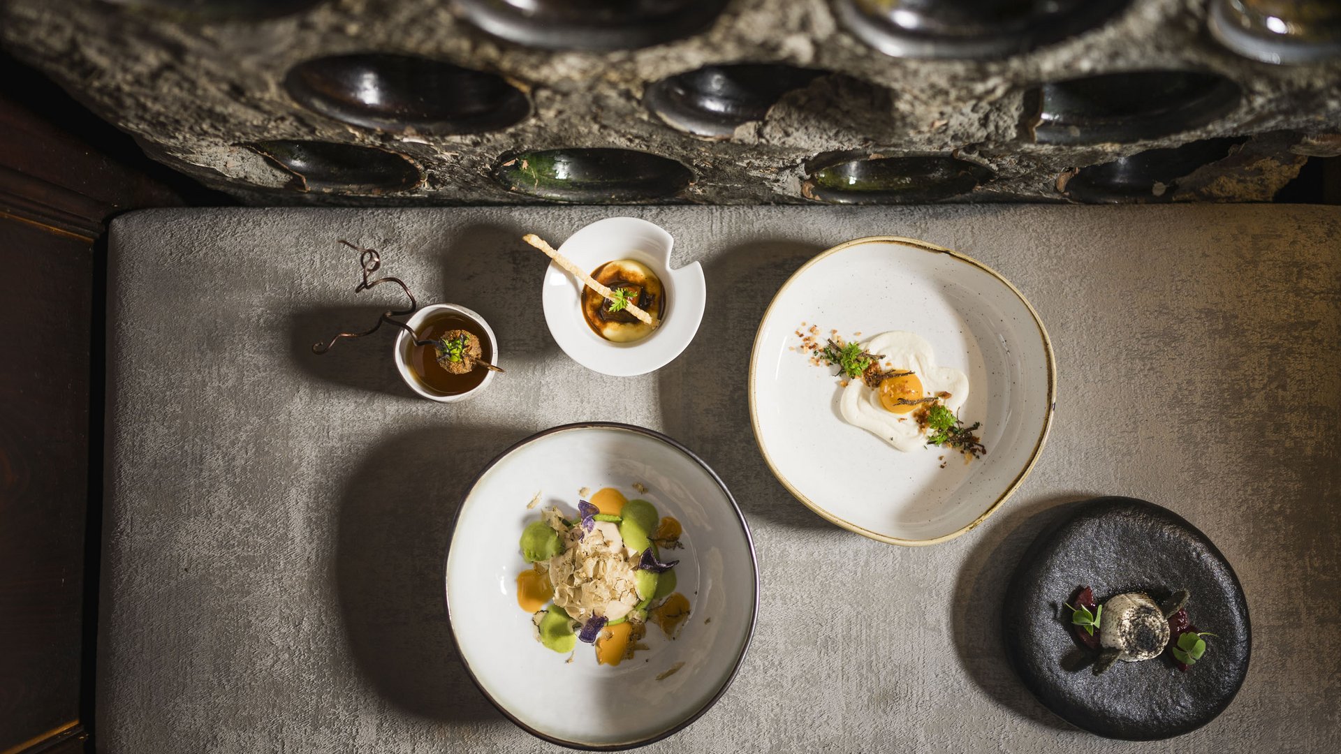 Five artistically plated gourmet dishes on a light surface.