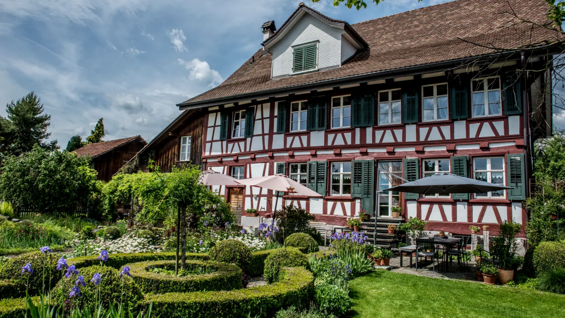 Traditional half-timbered house with garden and patio umbrellas