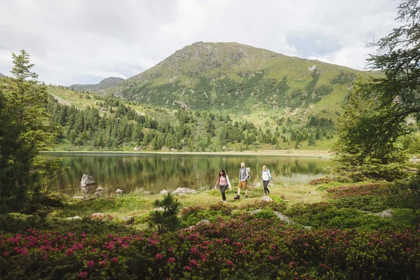 Murtal auf zwei Rädern © Karl Steinegger Drei Wanderer am Bergsee mit Bergen und blühenden Sträuchern im Vordergrund