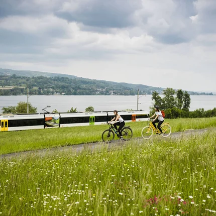 5 Radtouren durch den Thurgau © Ivo Scholz Zwei Radfahrer fahren auf einem Weg neben einer Bahnstrecke am See