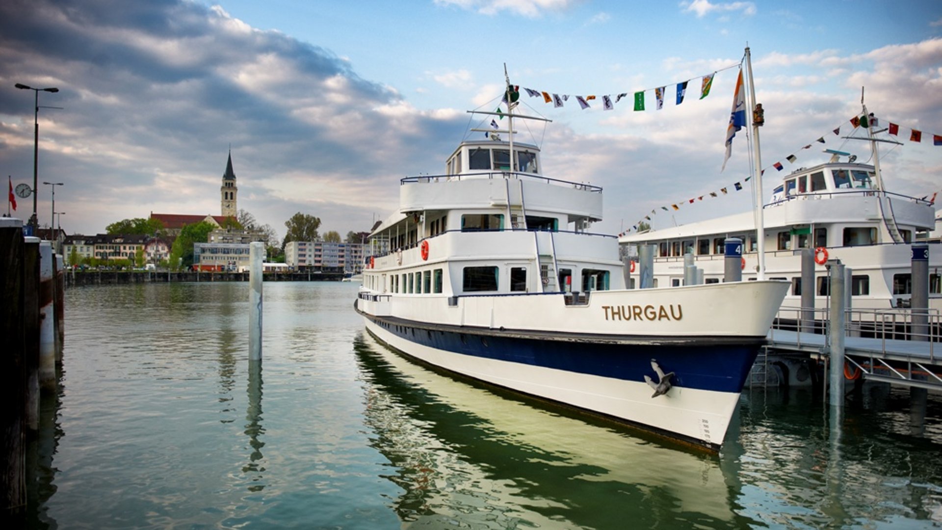 Passenger ship Thurgau docked at harbor with cloudy sky