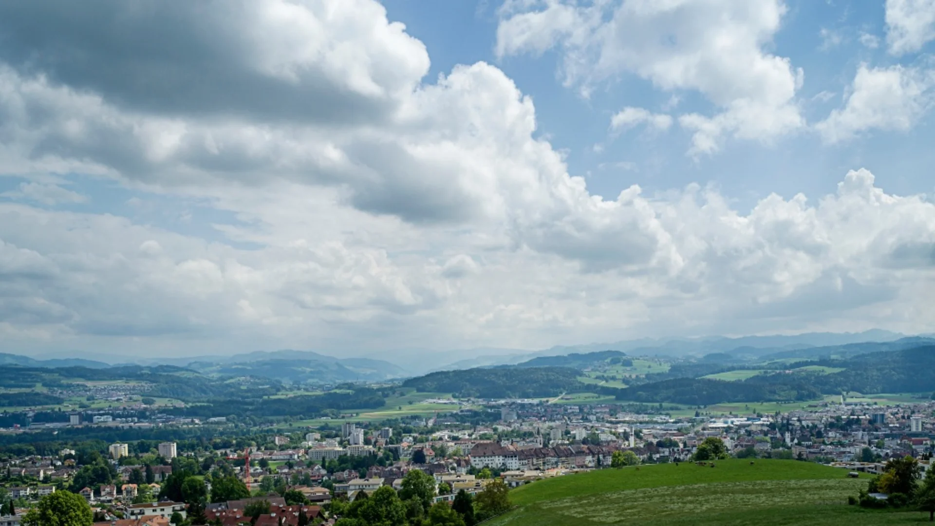 Blick auf eine Stadt mit Hügeln und bewölktem Himmel