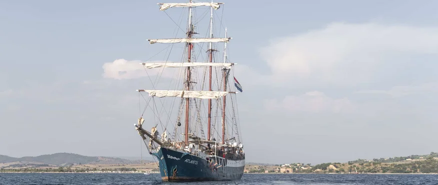 Segelschiff Atlantis auf ruhiger See vor Küstenlandschaft