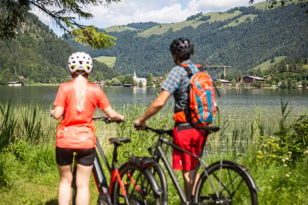 Radfahren und Wandern © Velontour Zwei Radfahrer blicken auf einen See mit Bergen im Hintergrund