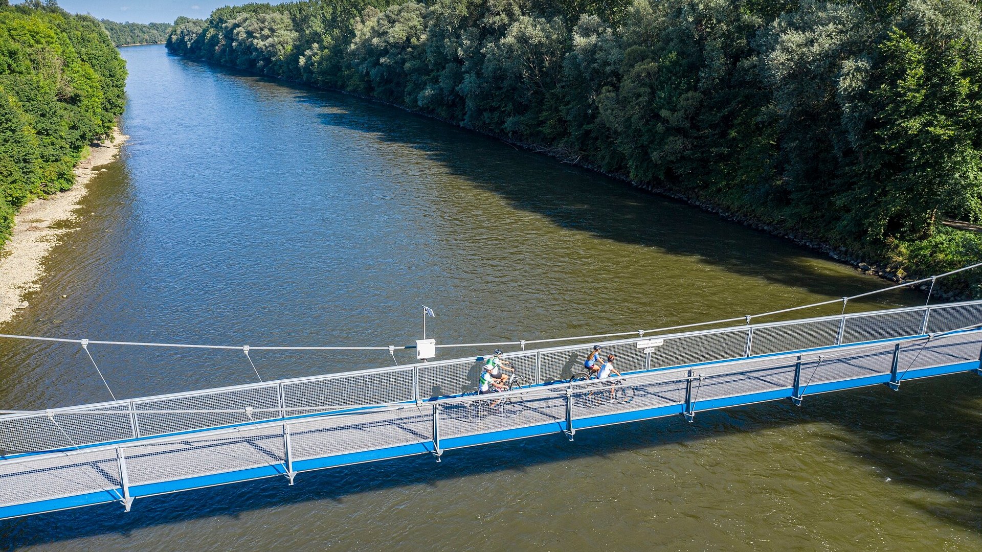 Cyclists on a blue pedestrian bridge over a river