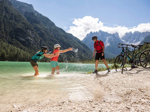 Drei Radfahrer spielen am Berghang am See mit Wasser an einem sonnigen Tag