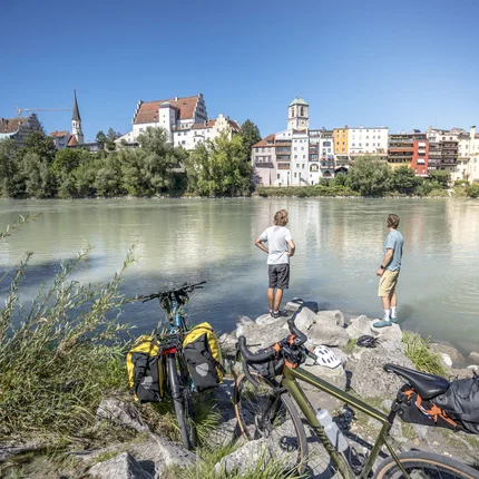 Twee fietsers bij rivier die uitkijken op een stad aan de overkant bij helder weer