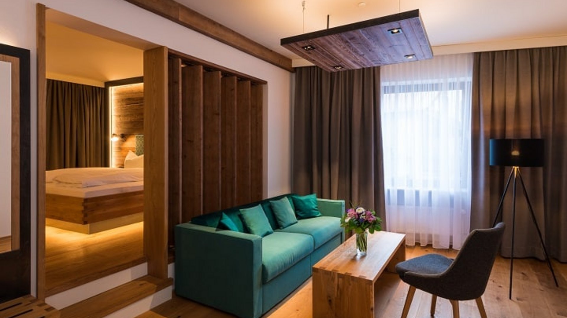 Modern living room with sofa, table, and adjacent bedroom with wooden accents