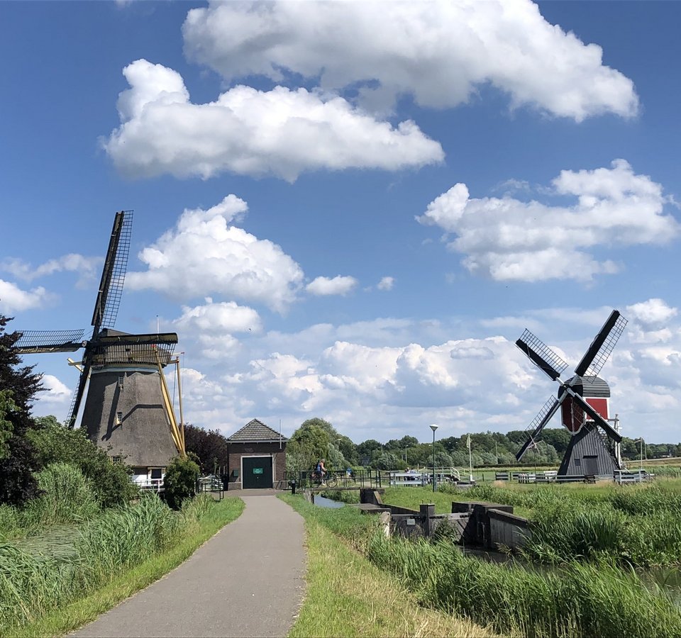 Weg zu zwei historischen Windmühlen unter einem bewölkten blauen Himmel
