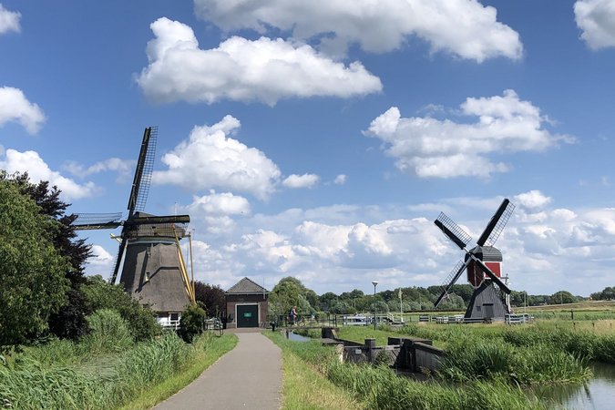 Weg zu zwei historischen Windmühlen unter einem bewölkten blauen Himmel