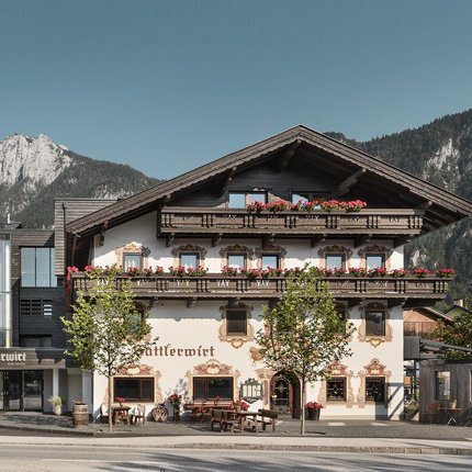 Traditional alpine house with flower decorations against mountains and clear sky
