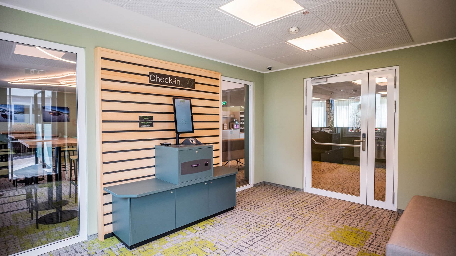 Modern hotel check-in area with kiosk and seating bench