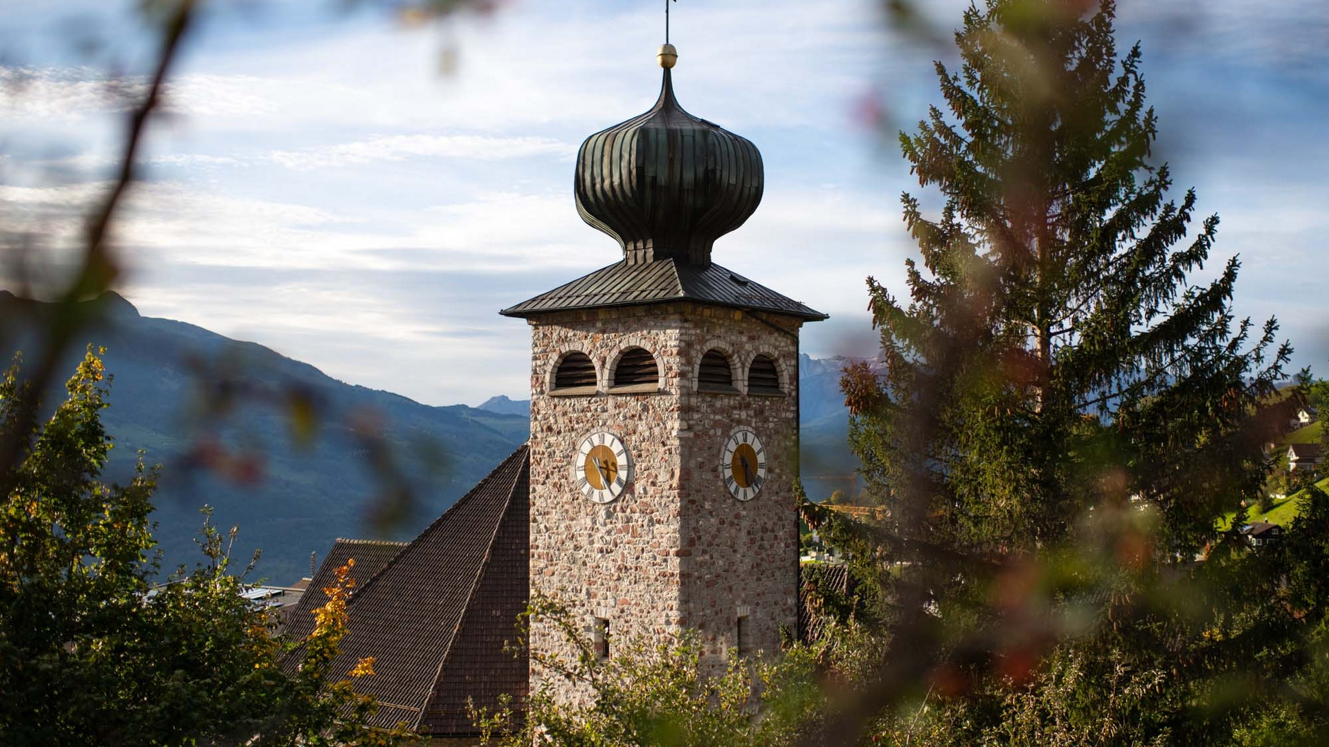 Stone church tower with onion dome in a mountain landscape