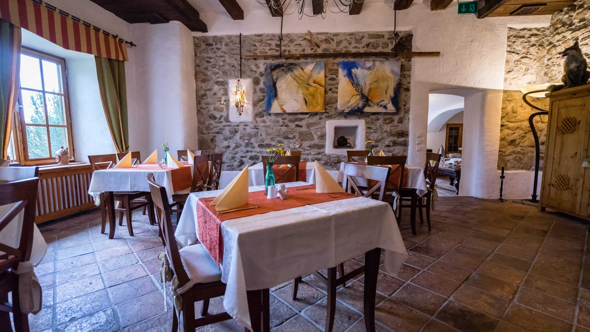 Rustic restaurant with stone wall, wooden furniture, and set tables