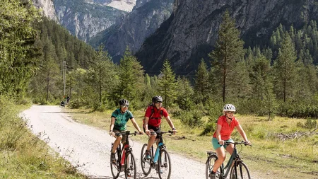 Radreisen in der Gruppe © Velontour Drei Radfahrer fahren auf einem Schotterweg in den Bergen bei sonnigem Wetter