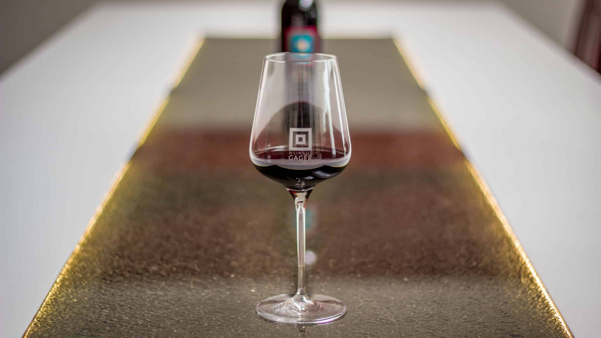 Wine glass with red wine on a distorted golden table runner