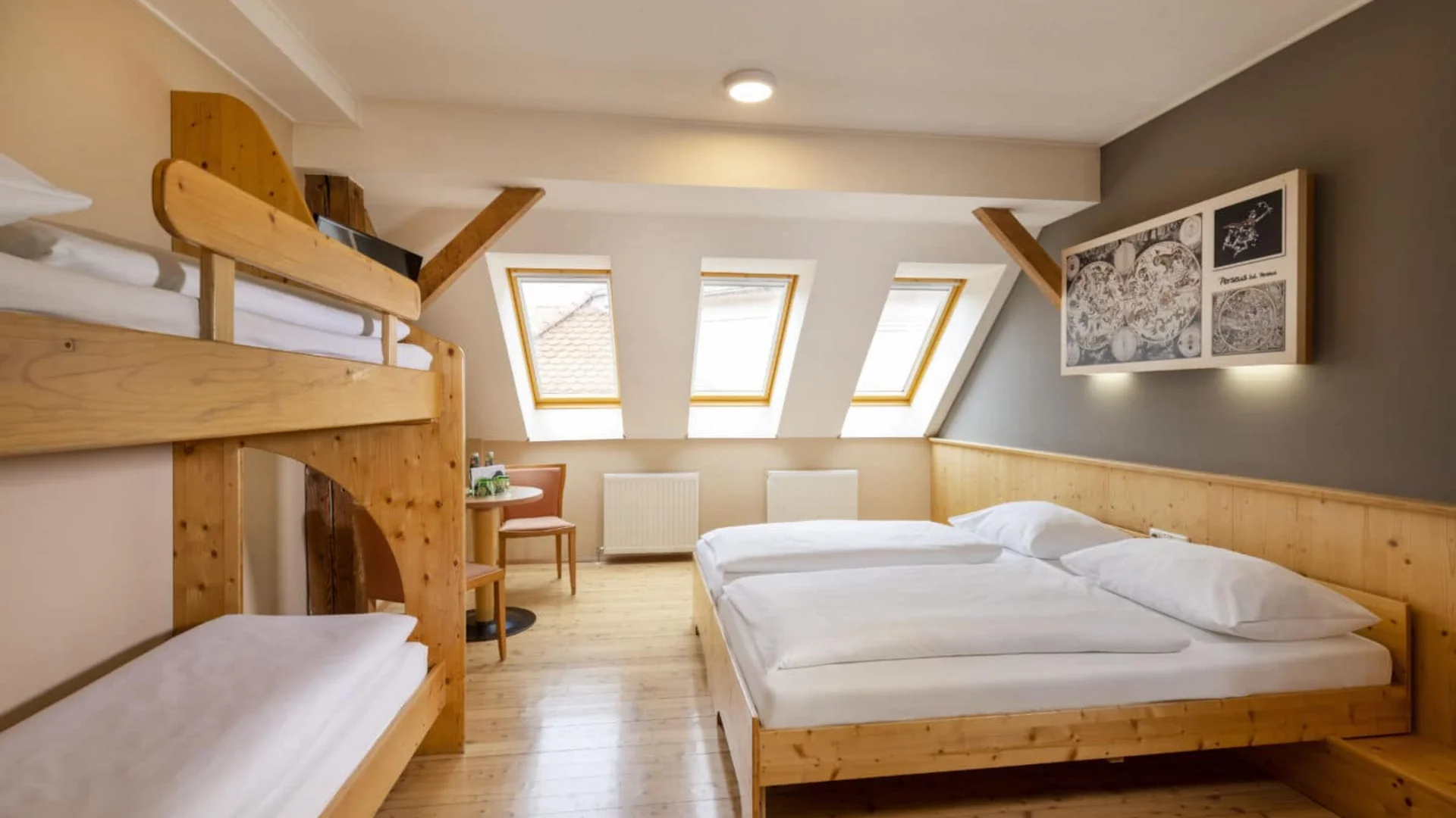 Bright bedroom with double bed and bunk beds under slanted roof windows