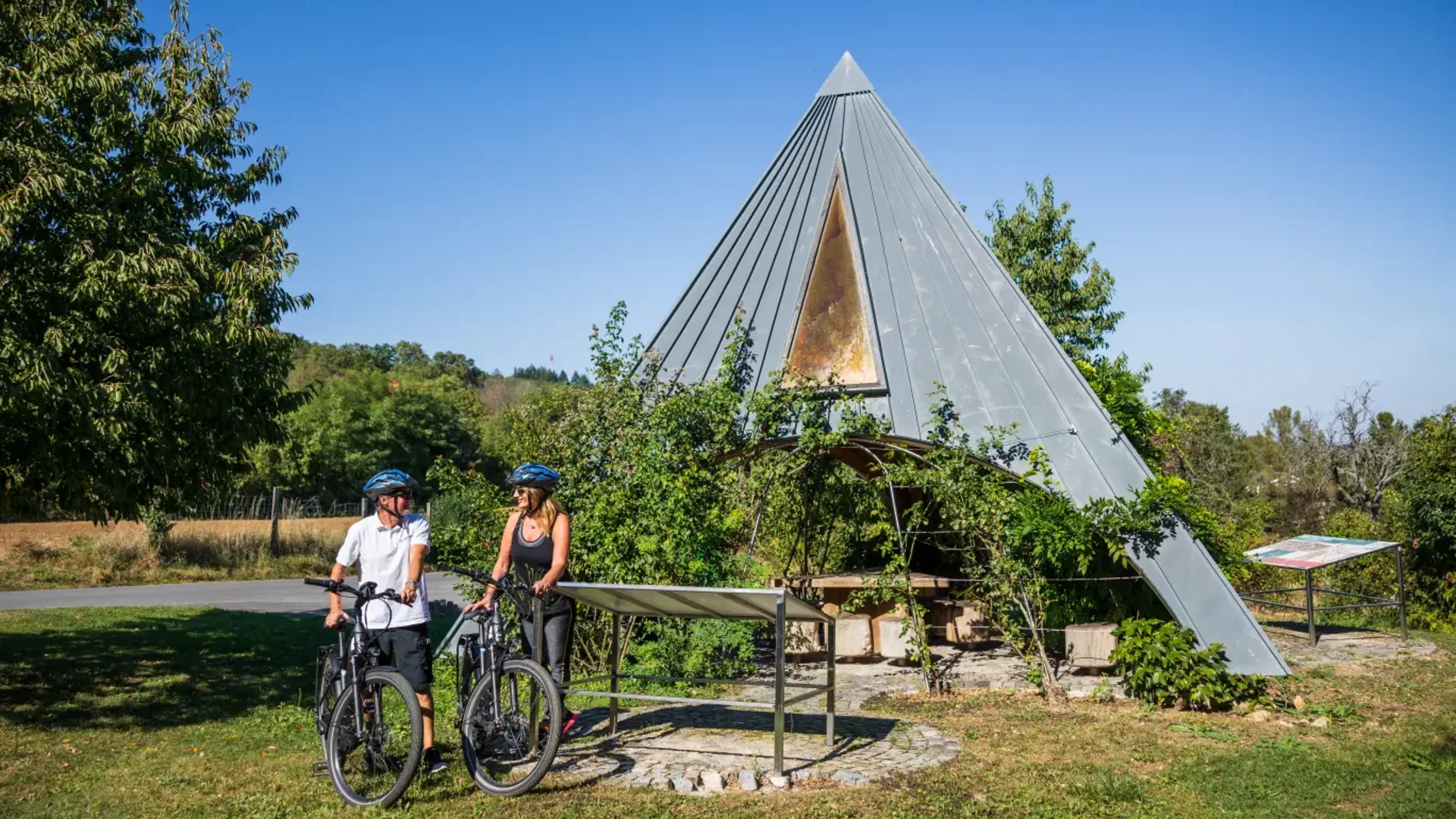 Tour-Detail © Maria Hollunder Zwei Radfahrer vor einer pyramidenförmigen Hütte in grüner Landschaft
