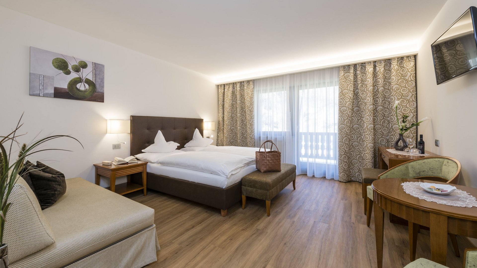 Bright hotel room with double bed, seating area, and balcony