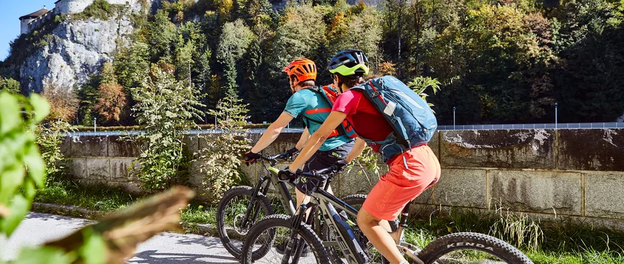 Zwei Radfahrer vor einer großen Burg auf einem sonnigen Tag