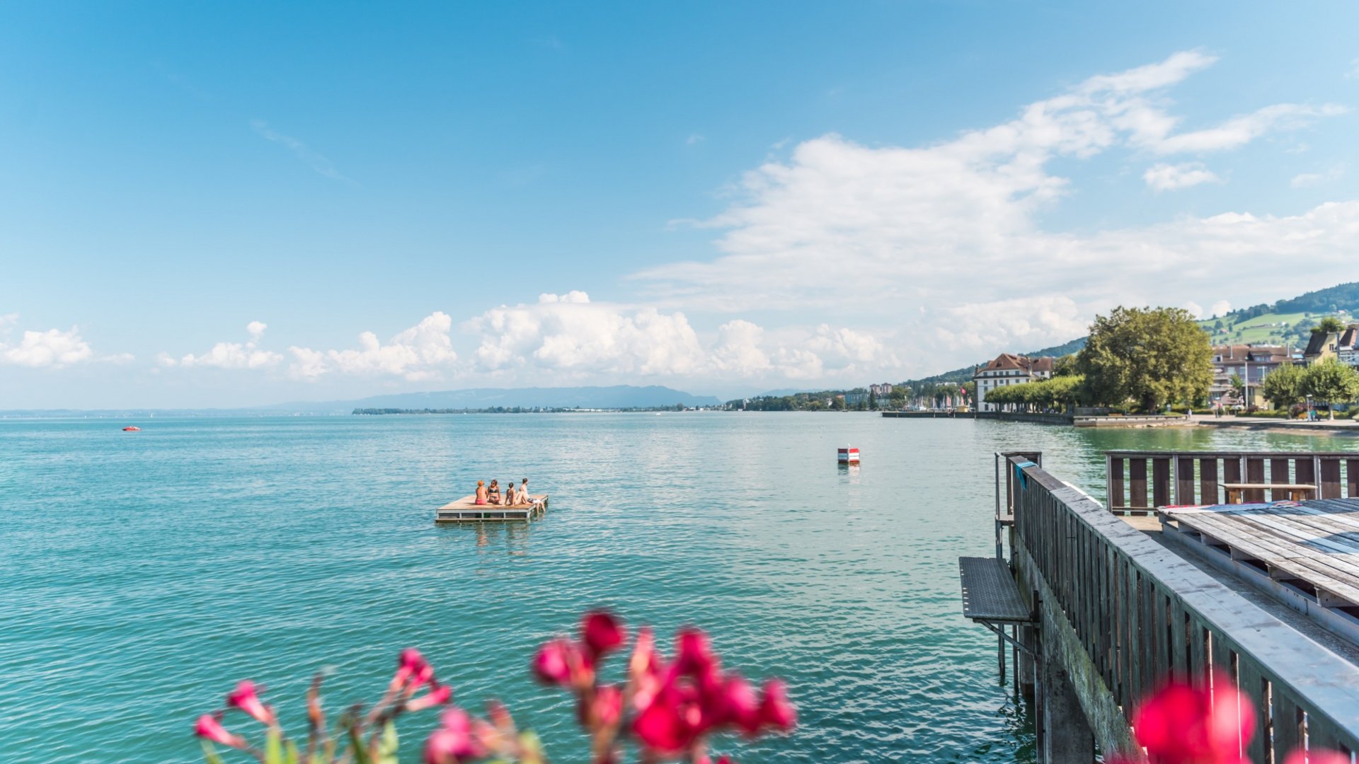 People on a raft on a lake with shoreline and hills in the background
