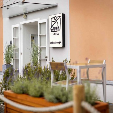 Entrance of JUFA Hotel with outdoor table and plants