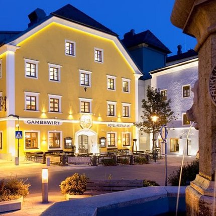 Illuminated yellow building next to a fountain at night in a town