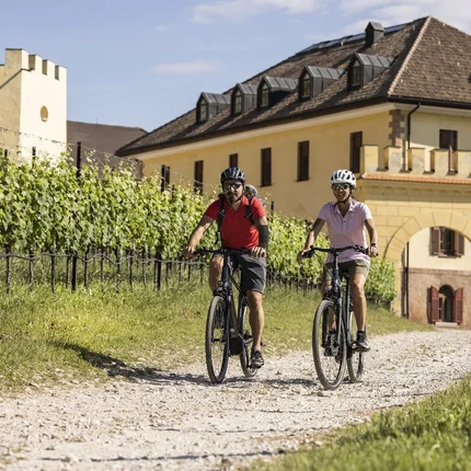 Twee fietsers op een zonnig pad bij een historisch gebouw