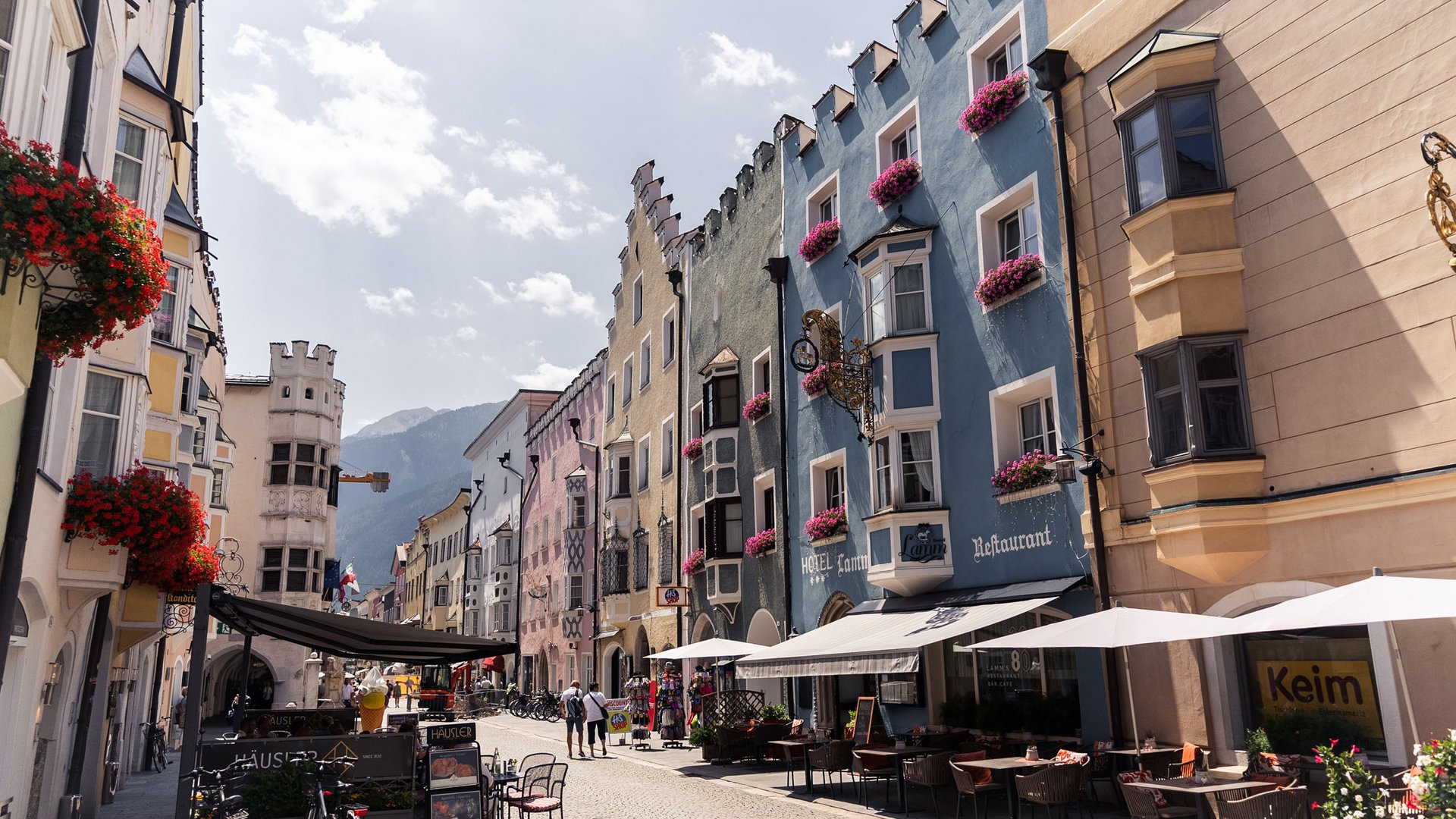 Colorful buildings with flowers and outdoor seating on a sunny old town street