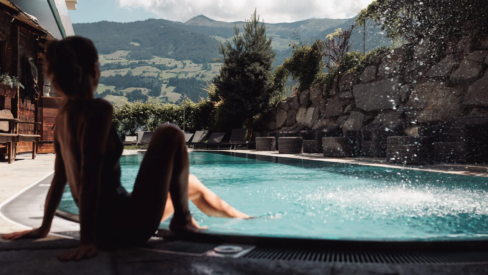 Person entspannt am Pool mit Bergblick im Hintergrund