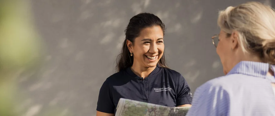 Frau zeigt einer anderen Frau eine Karte und lächelt freundlich