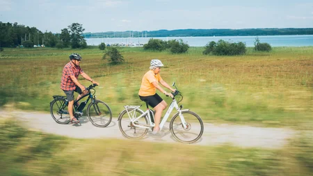 Älteres Paar fährt Fahrrad auf einem Weg neben einem See