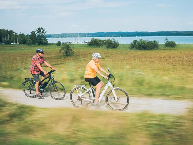 Älteres Paar fährt Fahrrad auf einem Weg neben einem See